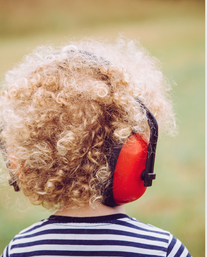 kind met koptelefoon als aanpassing op het te veel aan geluid